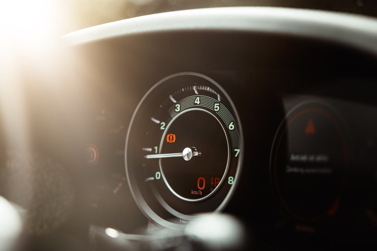 Close-up of a car dashboard instrument cluster with a warm light overlay flare