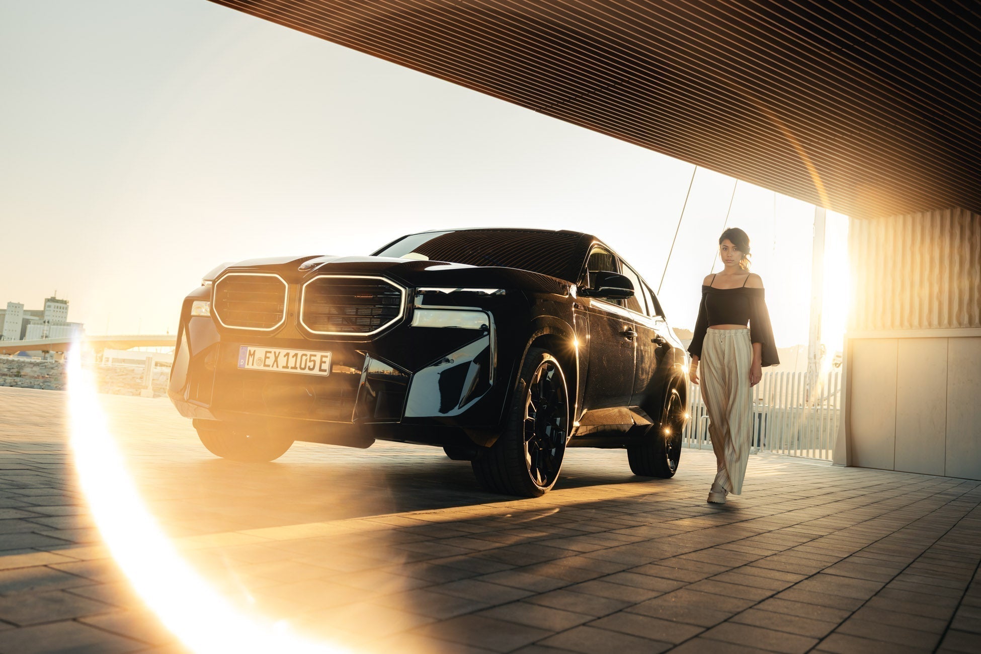 Black BMW SUV in a parking garage with a woman walking beside it, edited with Halo Pro ring of fire light overlay for a cinematic glow